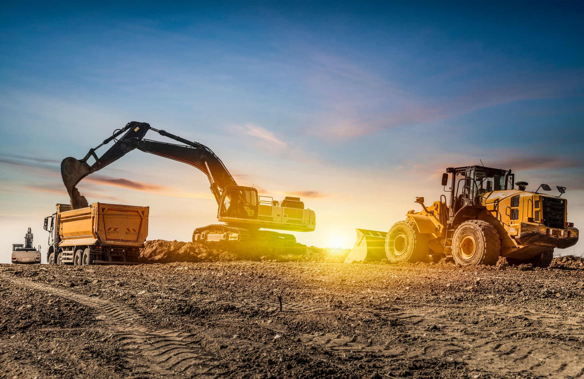 Excavators working on construction site at sunset